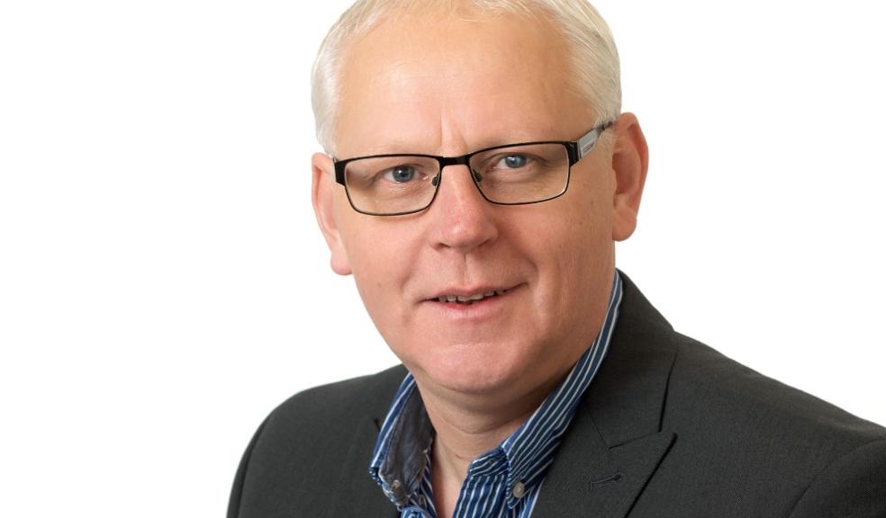 man in grey stripe shirt with open collar, glasses, white hair, wearing a suit