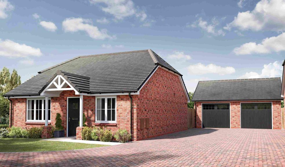 An image of a red brick bungalow with a garage and parking space